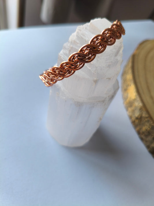 Pulseira artesanal de cobre entrelaçado sobre um cristal branco
